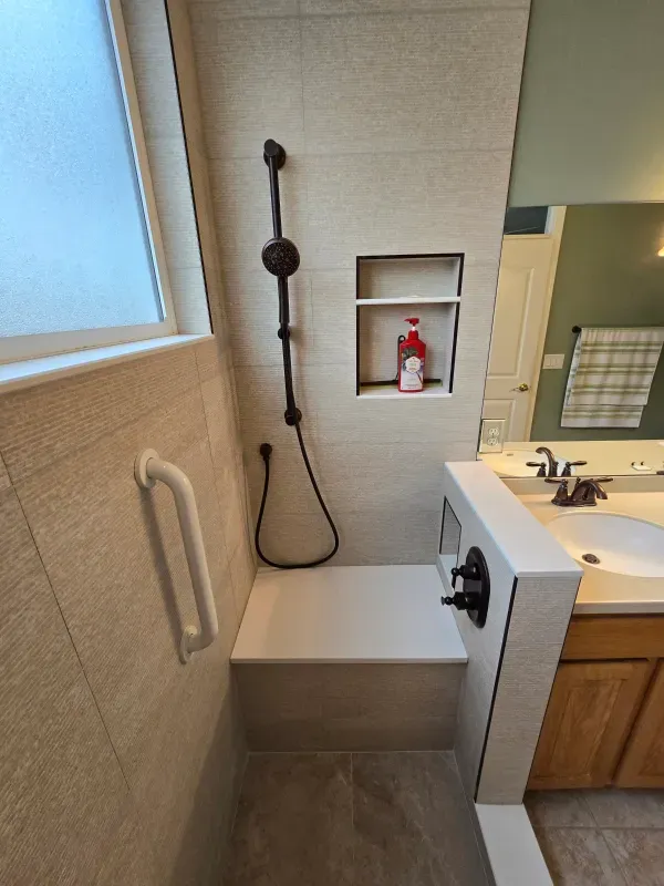 A bathroom with a sink , shower , and window.