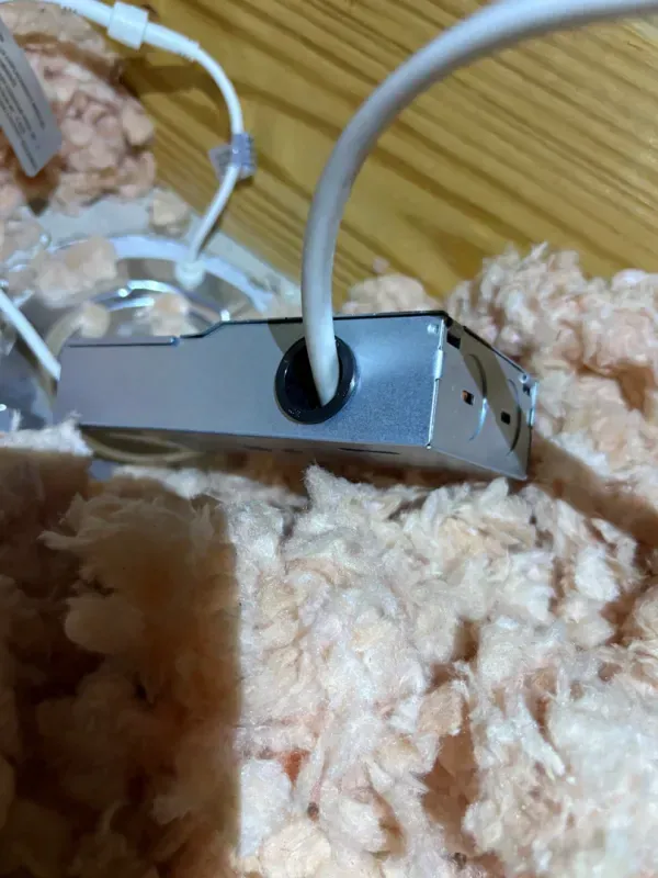 White cable plugged into a small silver device lying on beige carpet.