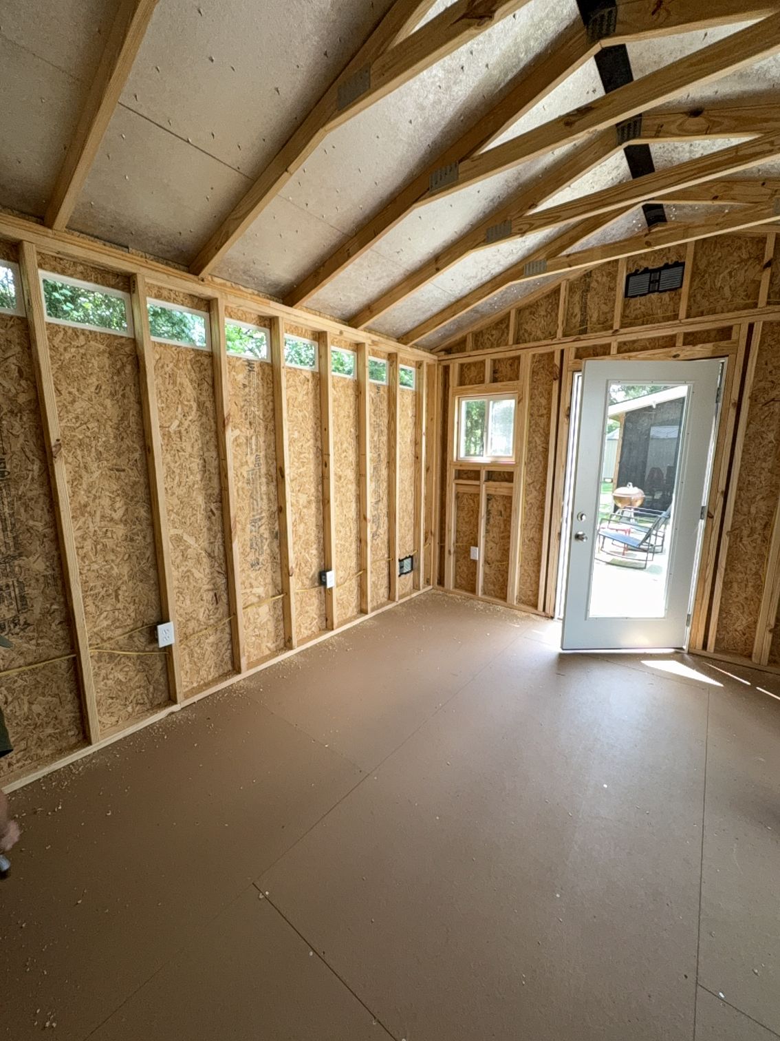 Interior of a framed room under construction with exposed insulation and a doorway to the outside