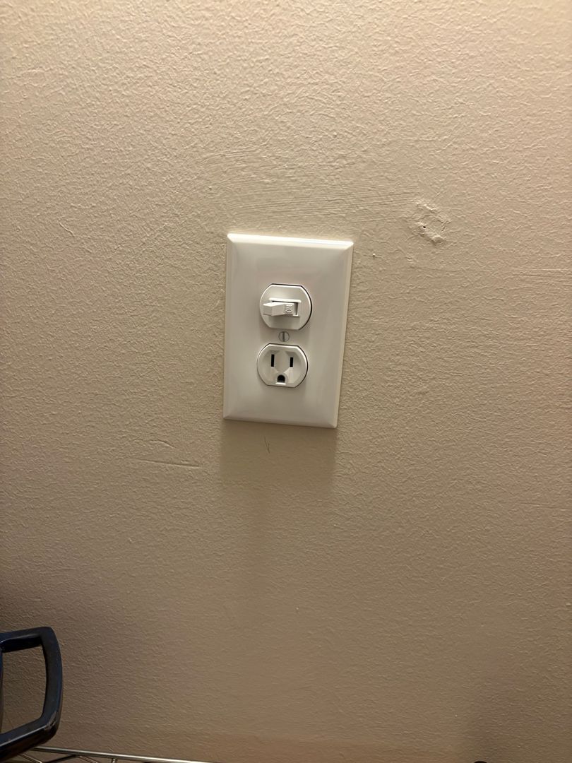 White electrical outlet on a beige wall, with a small scuff above it.