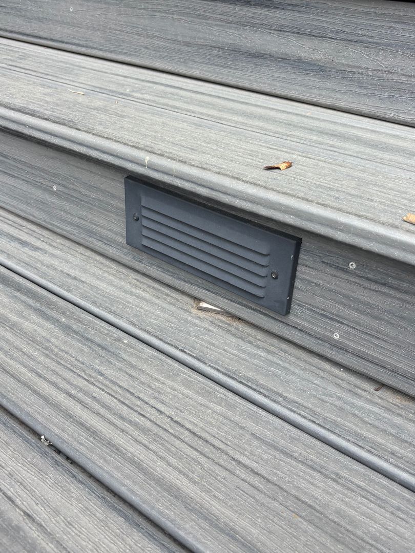 Rectangular dark gray vent on a light gray corrugated exterior wall