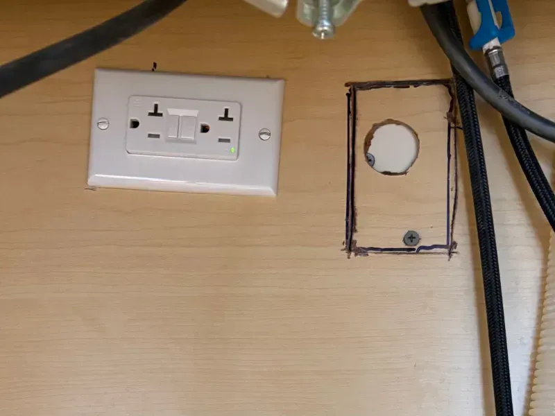 Wall with a white outlet plate and an empty rectangular cutout outlined in black marker.