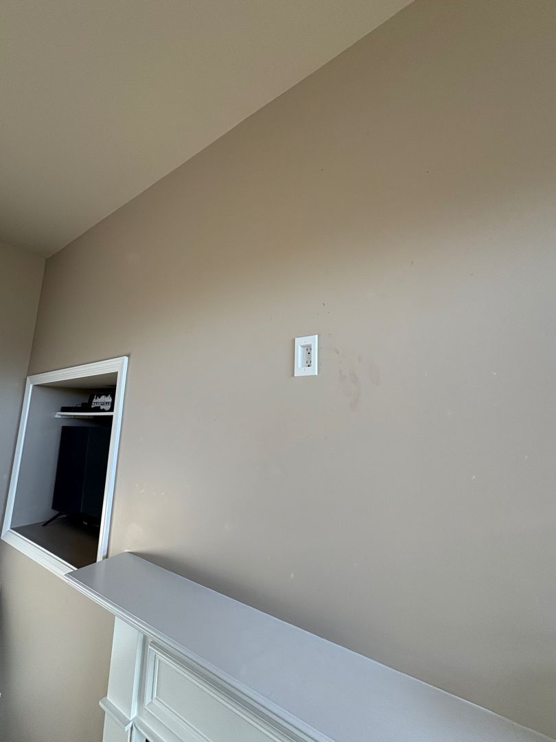 Empty beige interior wall with a small opening and white shelf ledge below