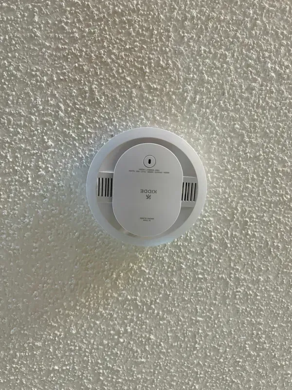 Round white smoke detector mounted on a textured ceiling