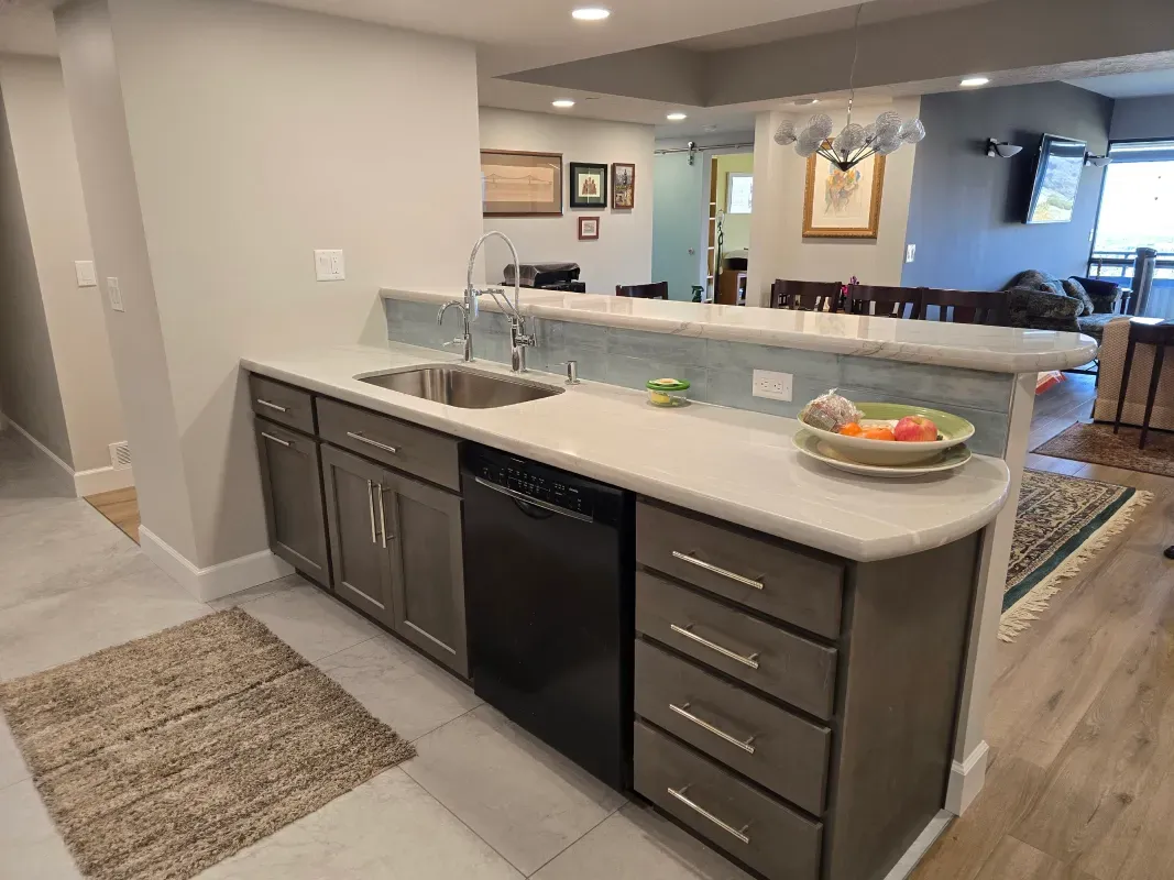 A kitchen with a sink , dishwasher , and cabinets.