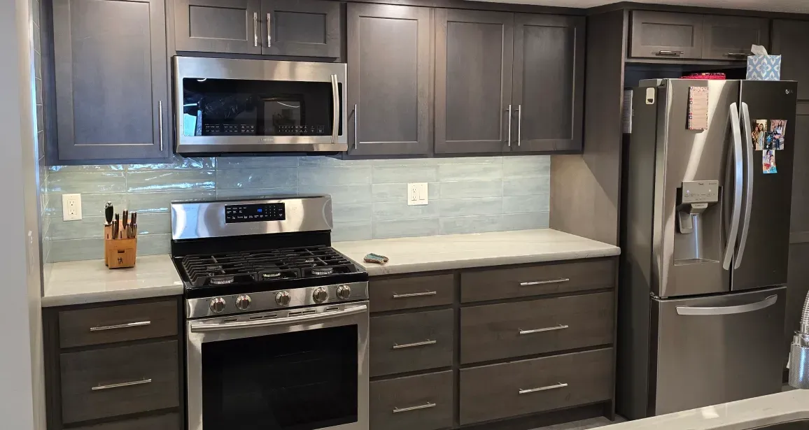 A kitchen with stainless steel appliances and gray cabinets.