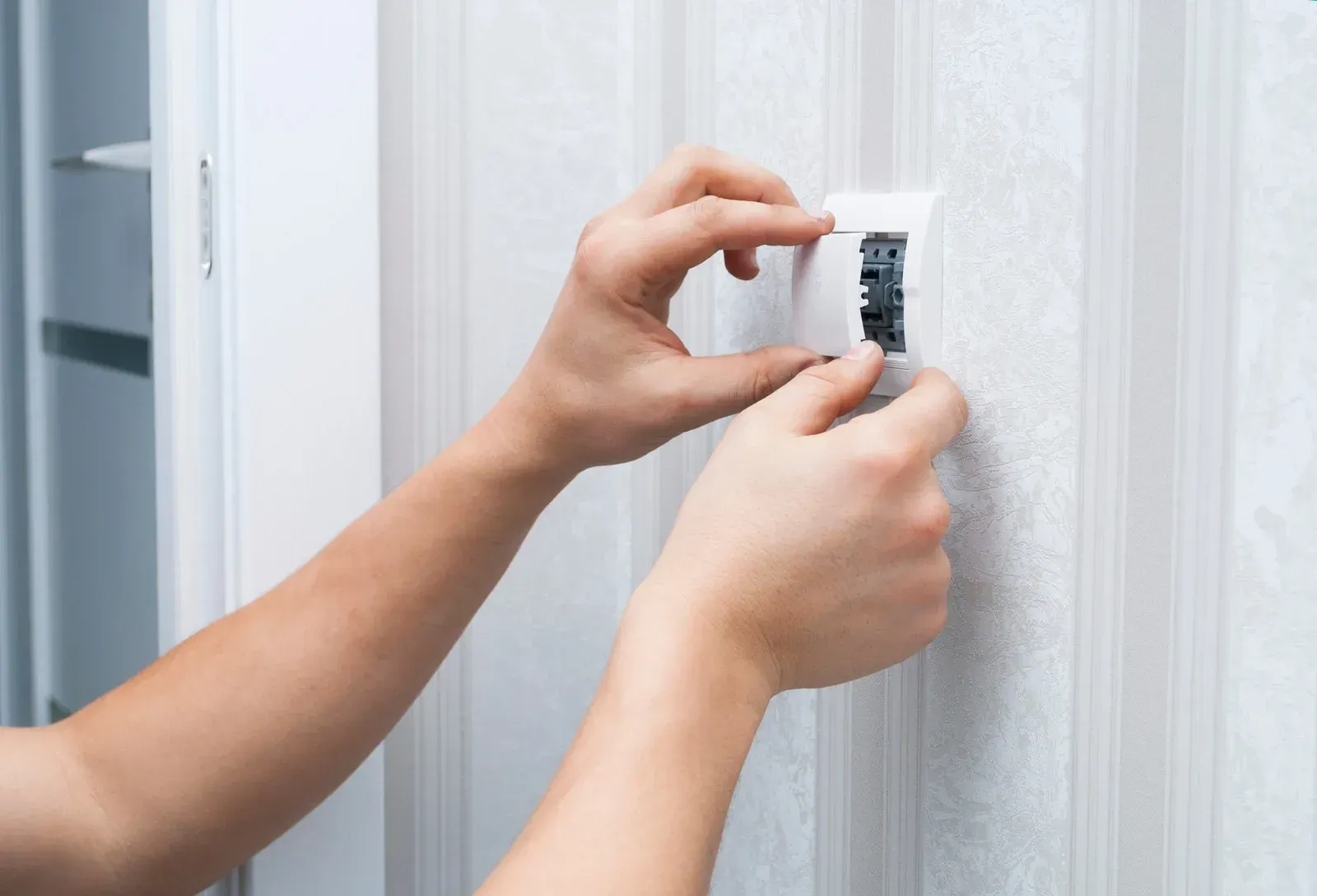 Hands applying white paint sample to a textured wall