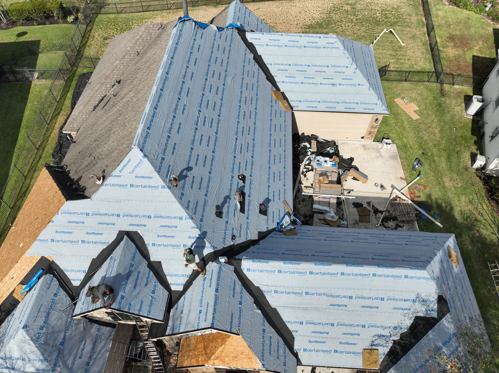 Overhead view of several dark gray shingled roofs of houses in a neighborhood.