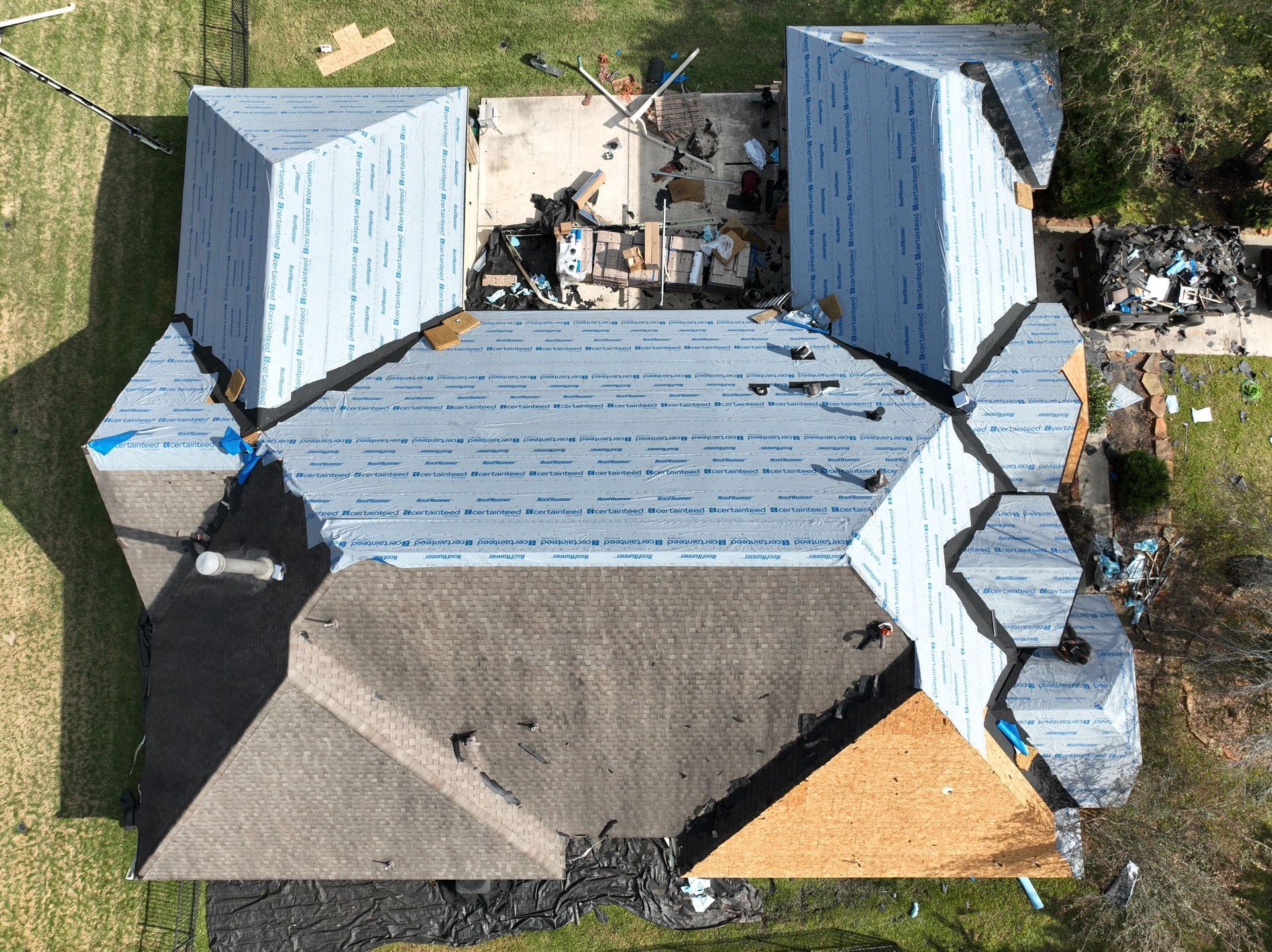 Overhead view of several dark gray shingled roofs of houses in a neighborhood.