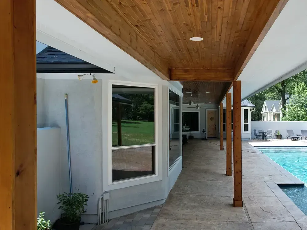 Covered patio with a wood ceiling, overlooking a pool and yard.