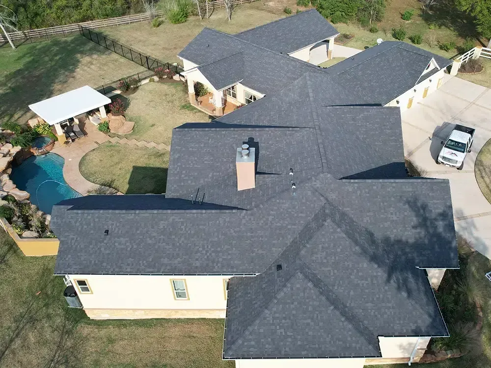 Overhead view of a house with a dark gray shingle roof, pool, and a white truck in the driveway.