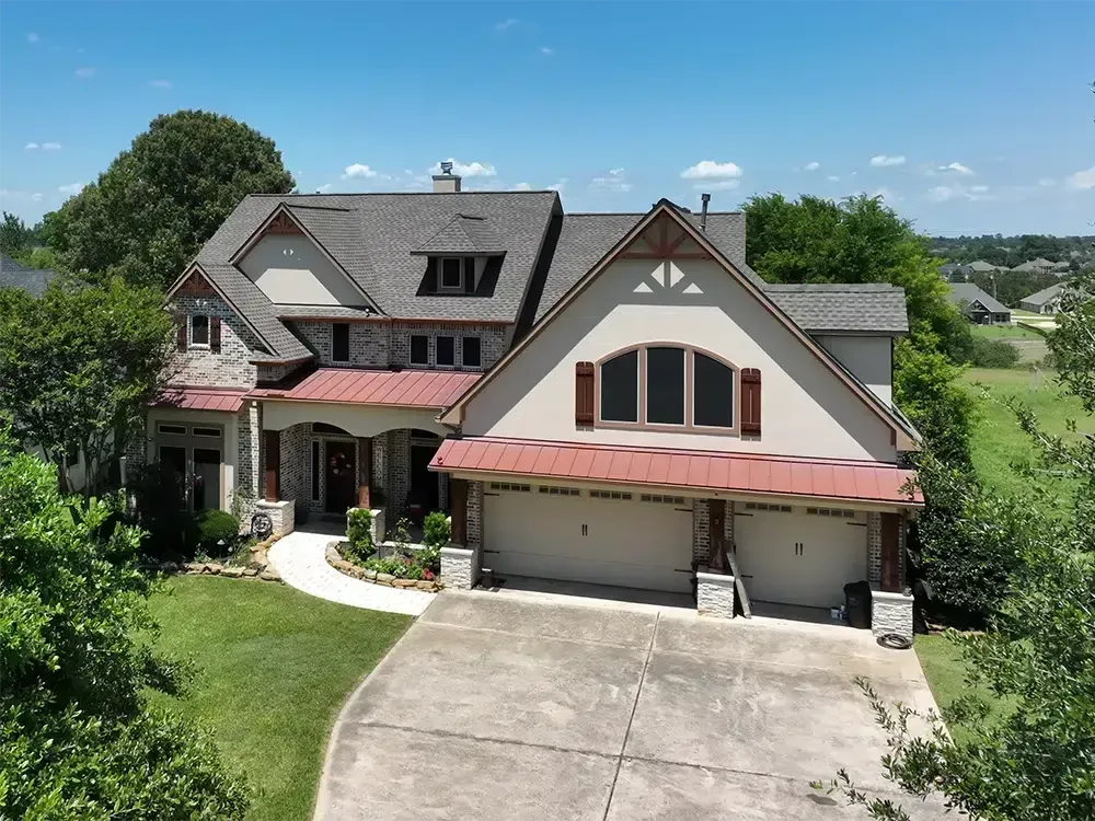 Two-story home with red roof and attached garage; light-colored stucco and stone exterior.