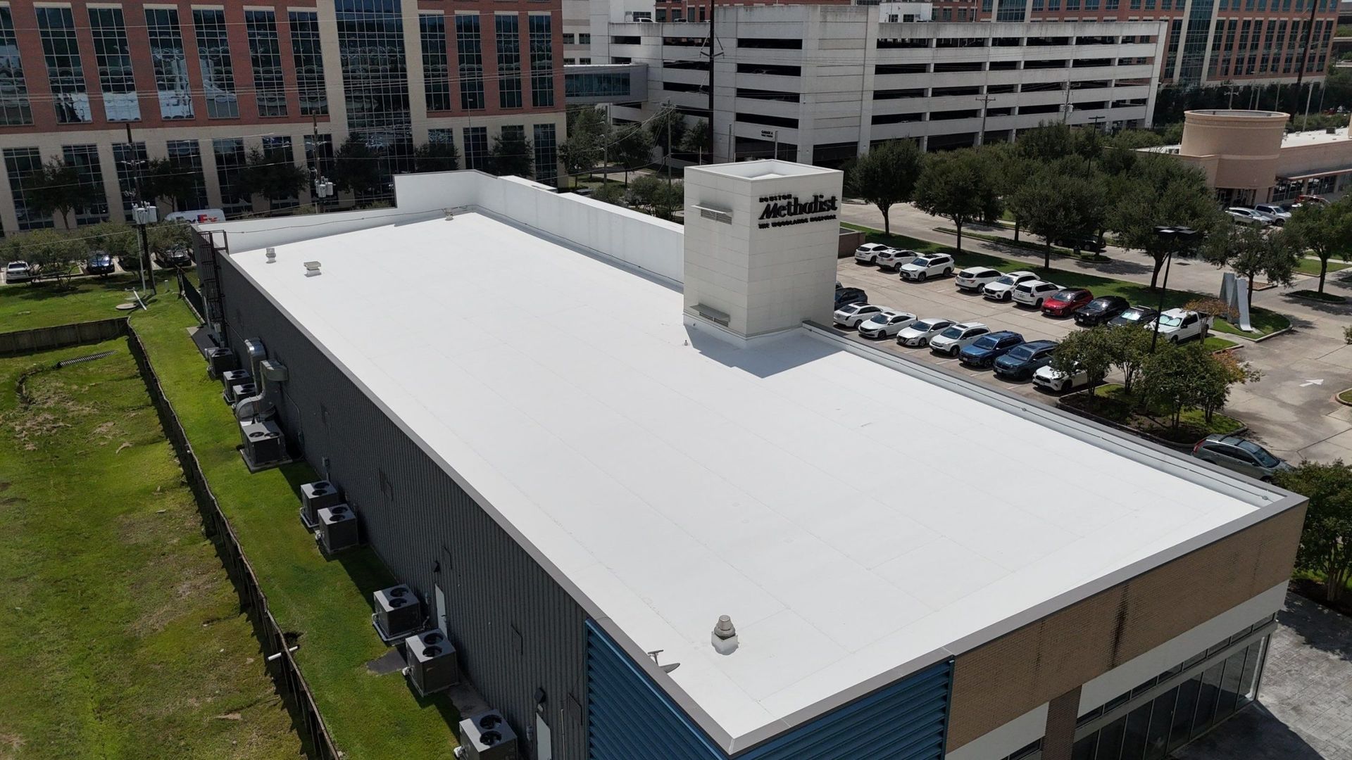 White flat commercial roof with an adjacent parking lot in an urban setting.