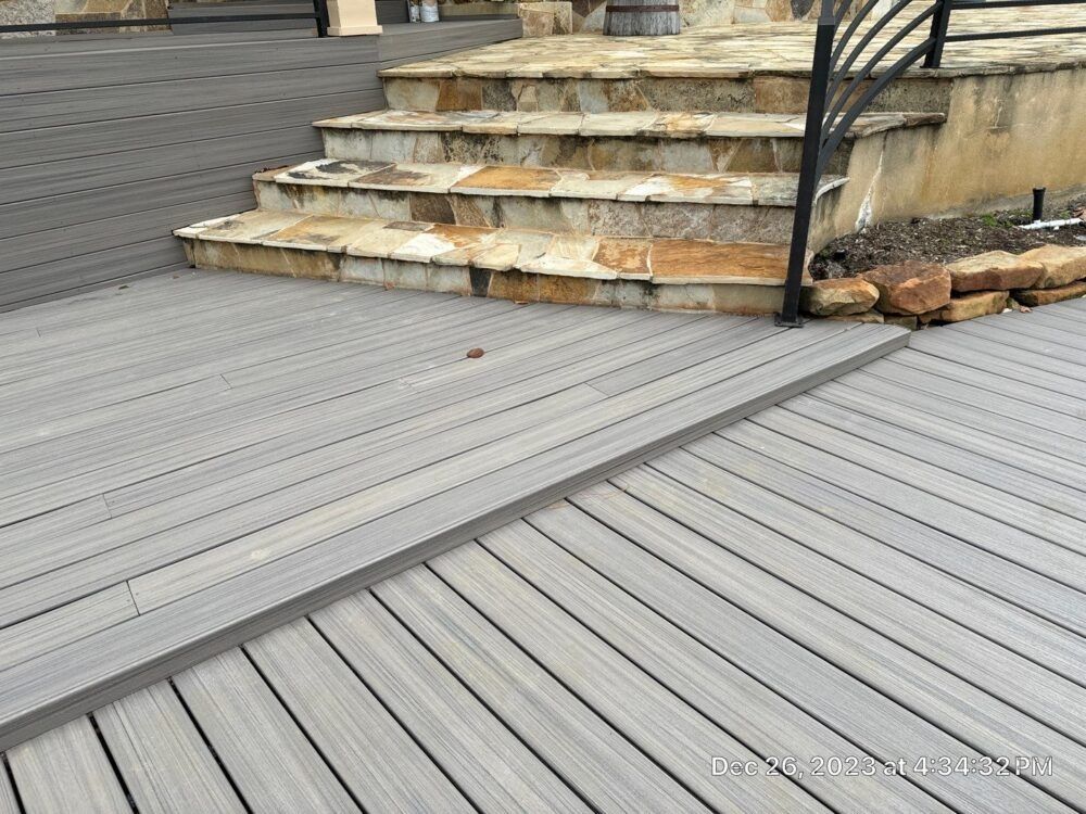 Gray composite deck with ramp and stone steps leading up.