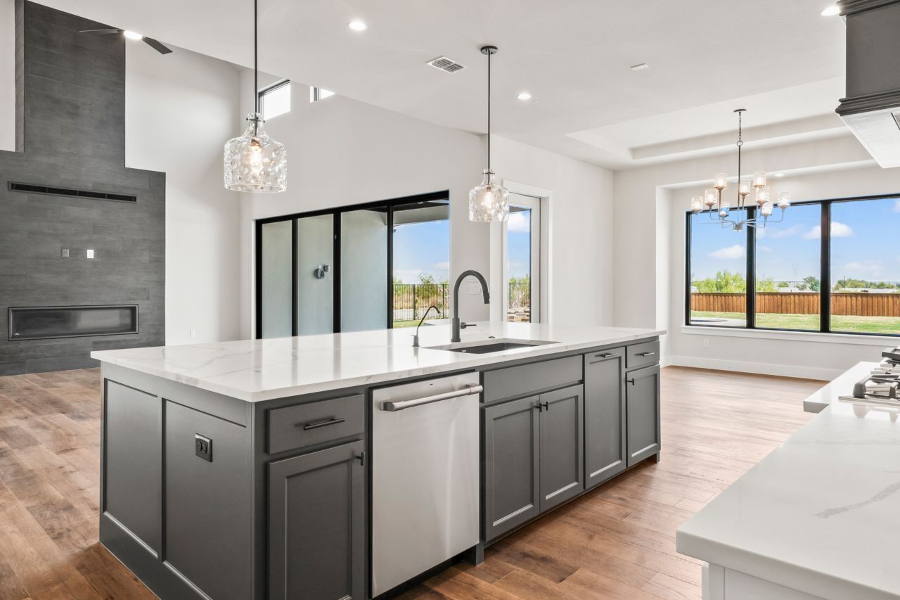 A modern kitchen with a large island and a view of a green field.