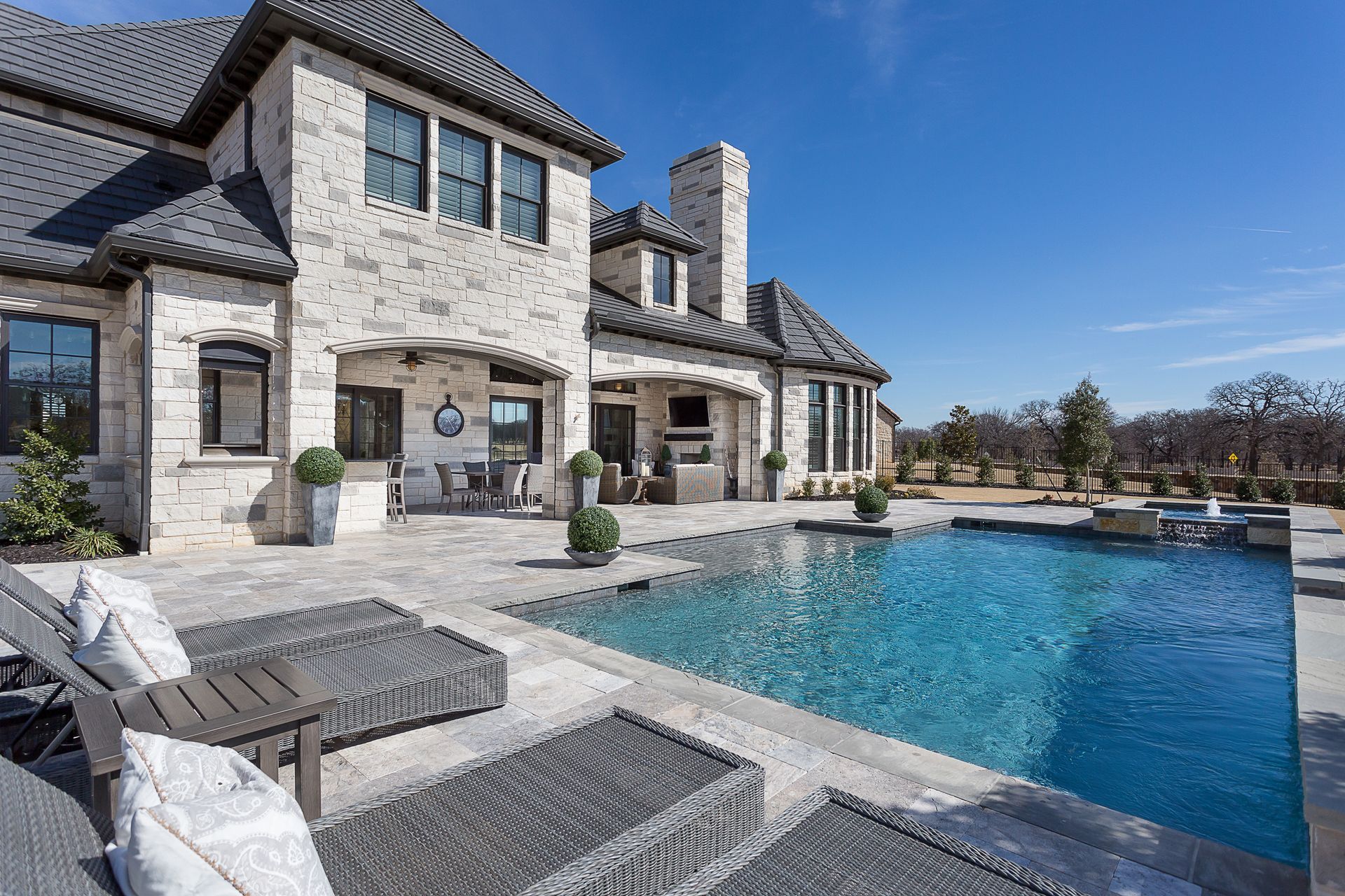 Stone-clad luxury home with a sparkling pool and outdoor living space