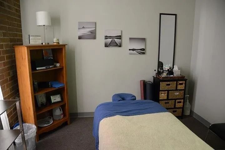 A room with a massage table and a mirror.