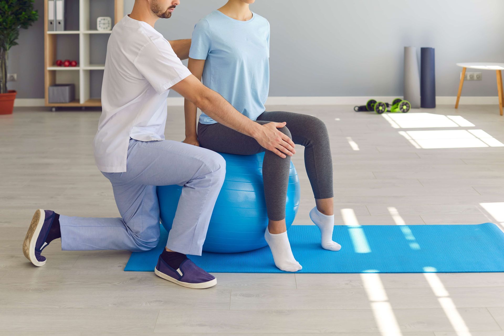 A man and a woman are sitting on a blue exercise ball.