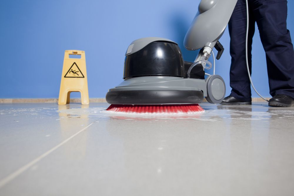 A Man Is Cleaning a Tiled Floor with A Machine — North Coast Commercial Cleaners In Bli Bli, QLD