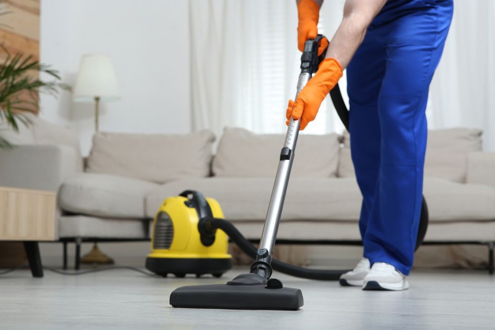 A Person Is Using a Vacuum Cleaner in A Living Room — North Coast Commercial Cleaners In Maroochydore, QLD
