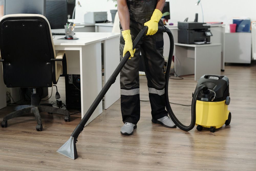 A Man Is Cleaning the Floor of An Office with A Vacuum Cleaner — North Coast Commercial Cleaners In Bli Bli, QLD
