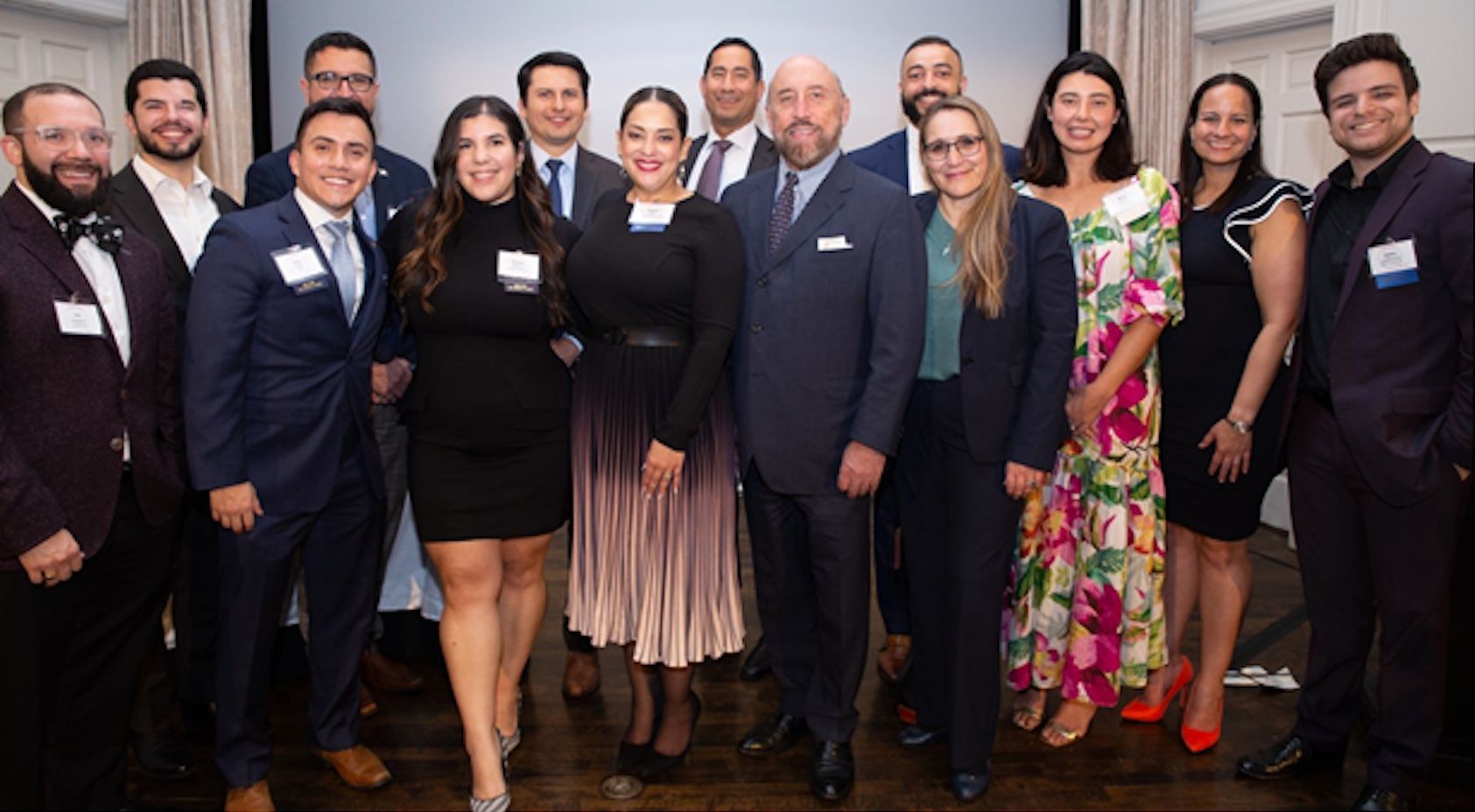 A group of people in formal attire posing together at an indoor event.