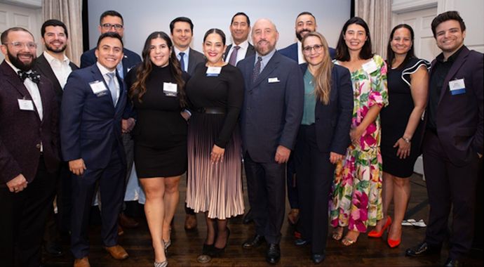 A group of people in formal attire posing together at an indoor event.