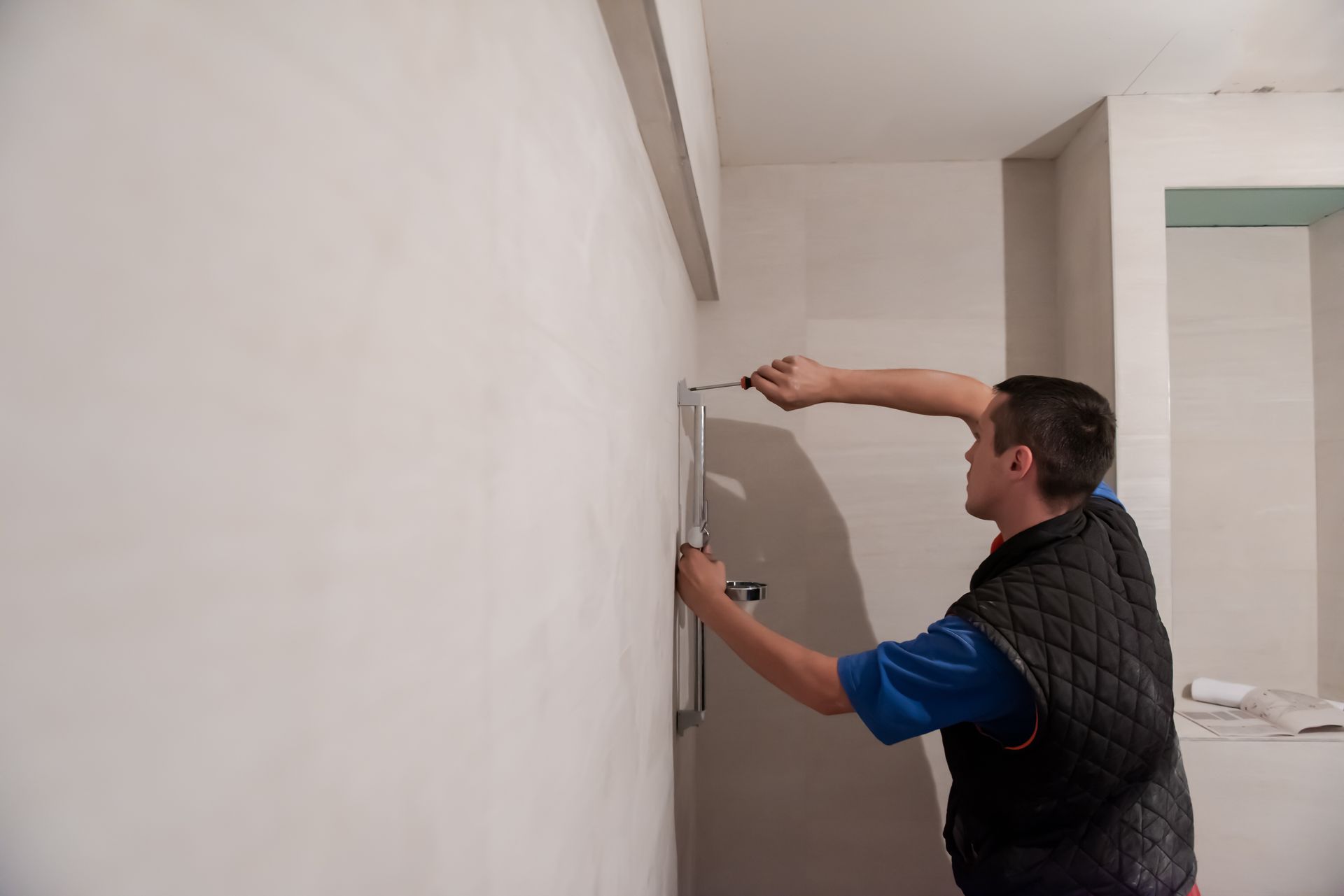A man is measuring a wall with a tape measure.