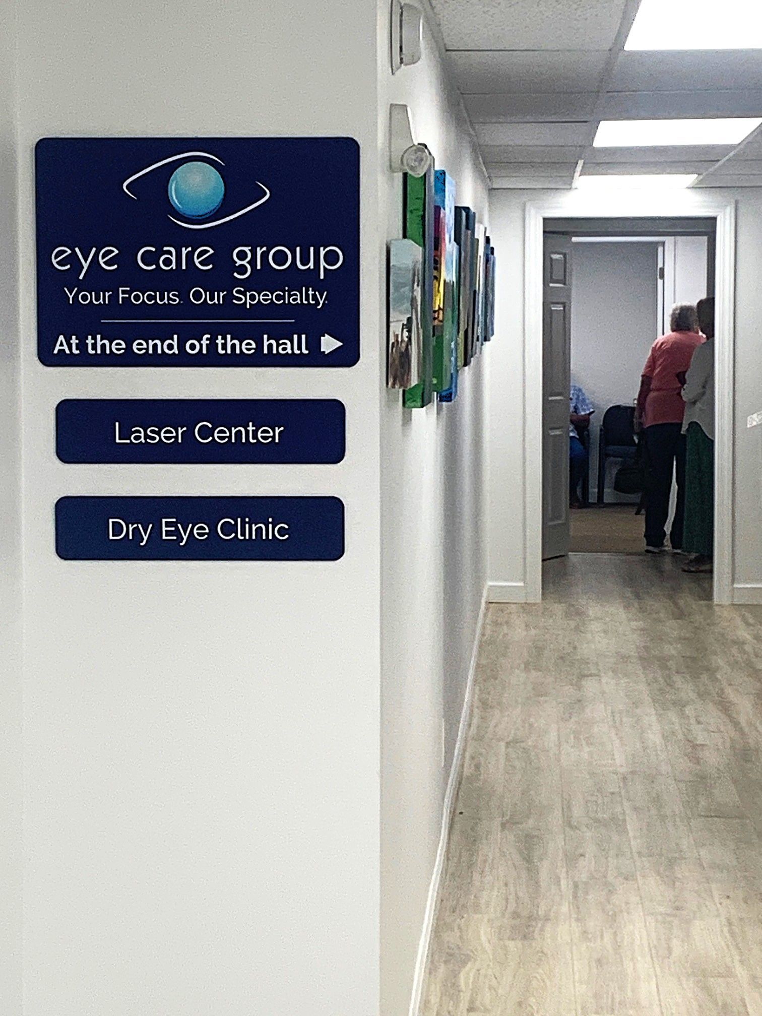 Hallway with signs for Eye Care Group, Laser Center, and Dry Eye Clinic; person at far end.