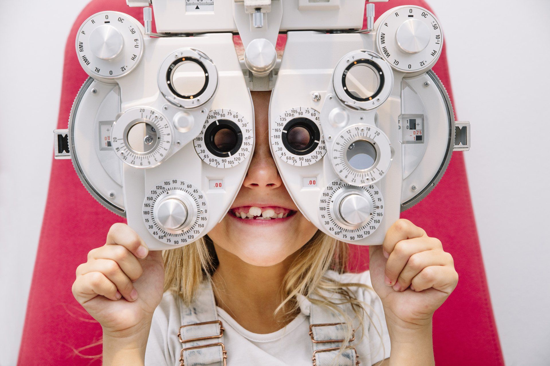 Child smiling behind eye exam equipment
