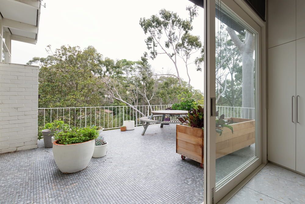 A Balcony With A Picnic Table And Potted Plants — Corrimal Ceramic Tiles Pty Ltd in Wollongong, NSW