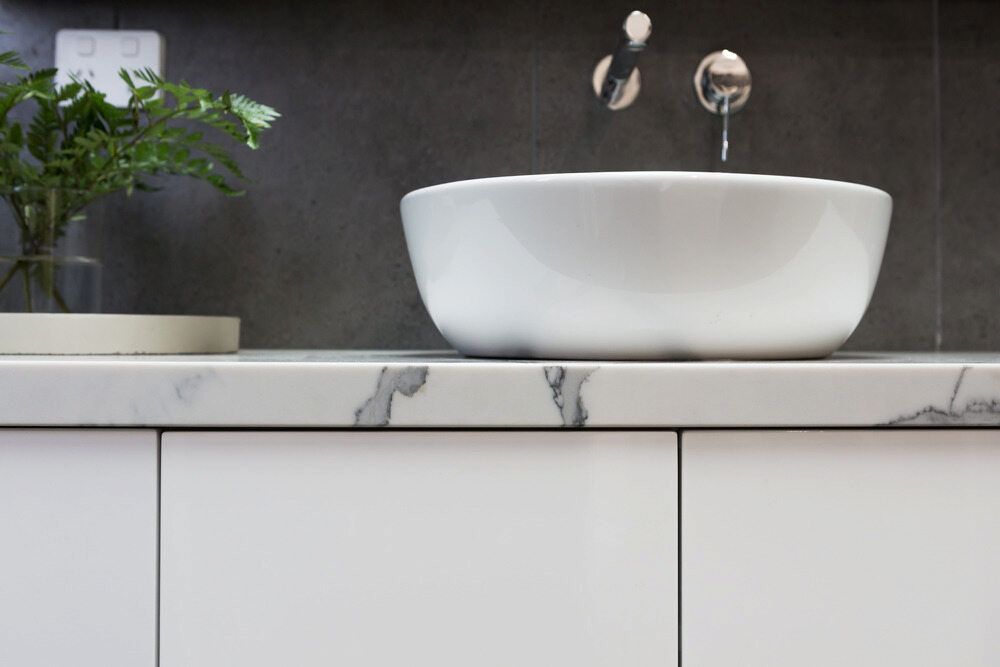 A White Sink Is Sitting On Top Of A Marble Counter In A Bathroom — Corrimal Ceramic Tiles Pty Ltd in Thirroul, NSW
