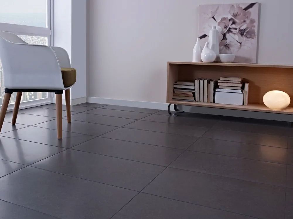 A Living Room With A Chair And A Shelf Full Of Books — Corrimal Ceramic Tiles Pty Ltd in Corrimal, NSW