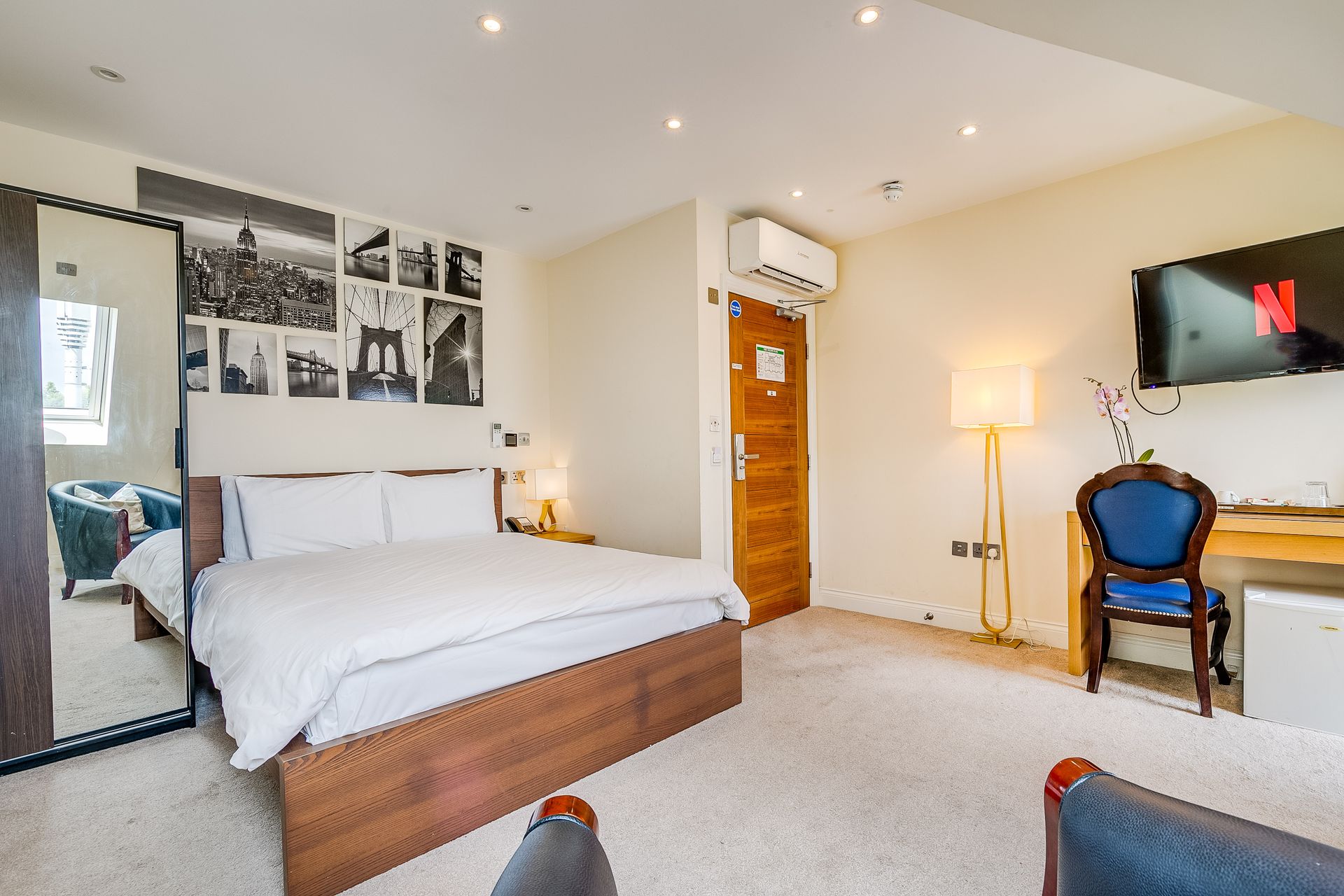 A hotel room with a bed , chair , desk and television.