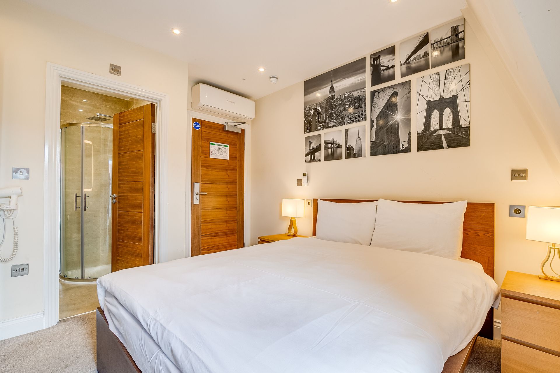 A hotel room with a king size bed and a walk in shower.