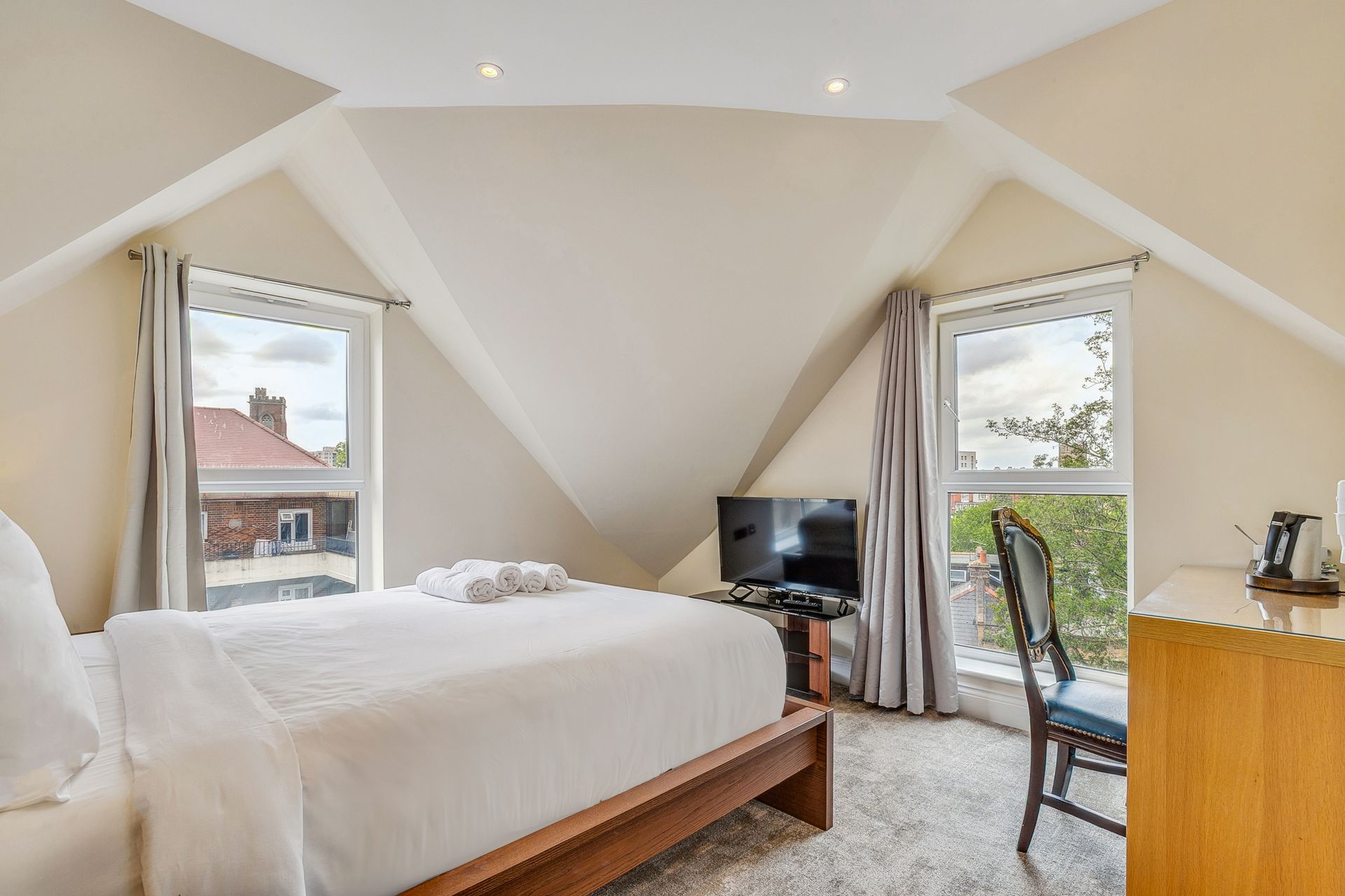 A bedroom with a bed , desk , chair and television.