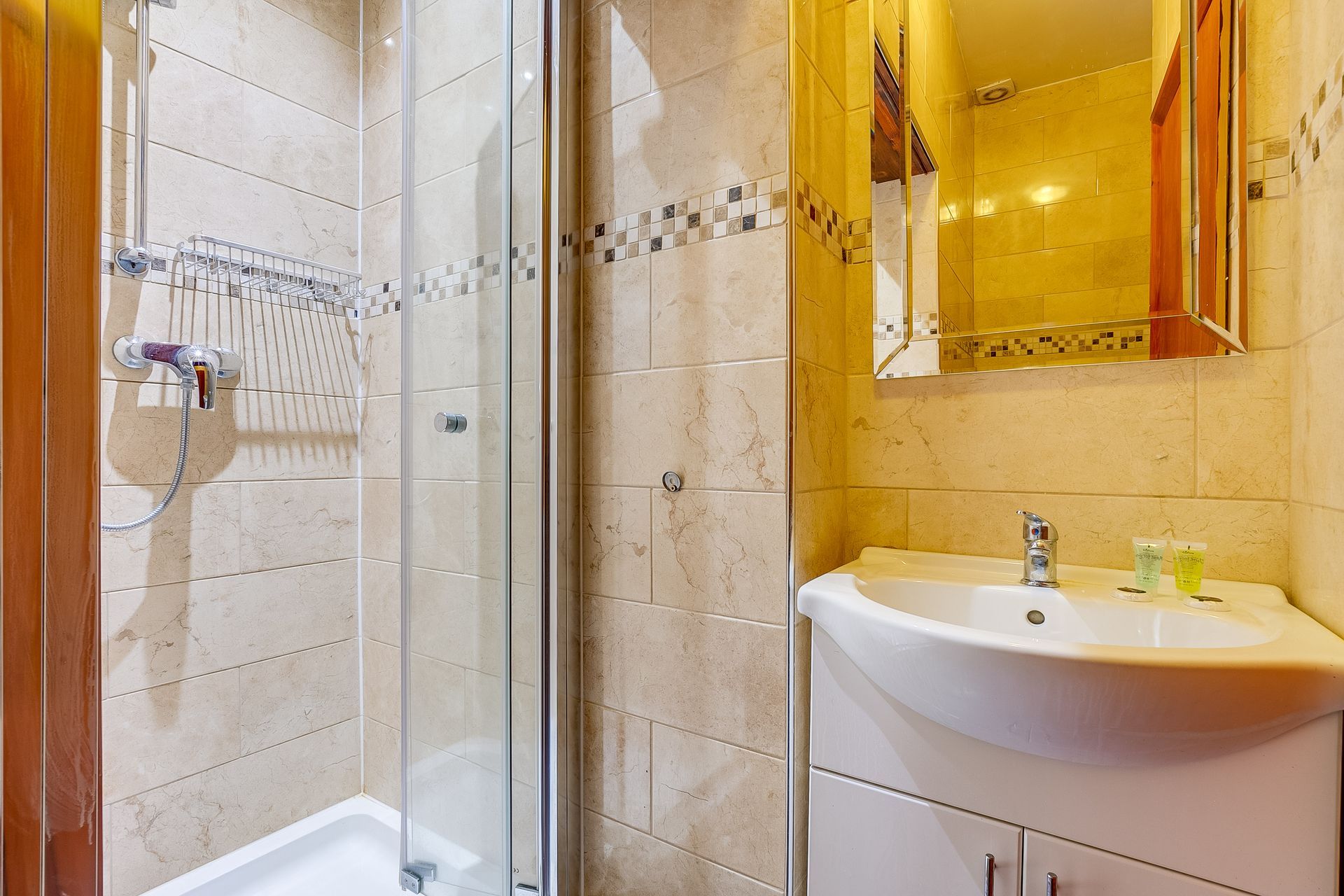 A bathroom with a sink , mirror and shower stall.