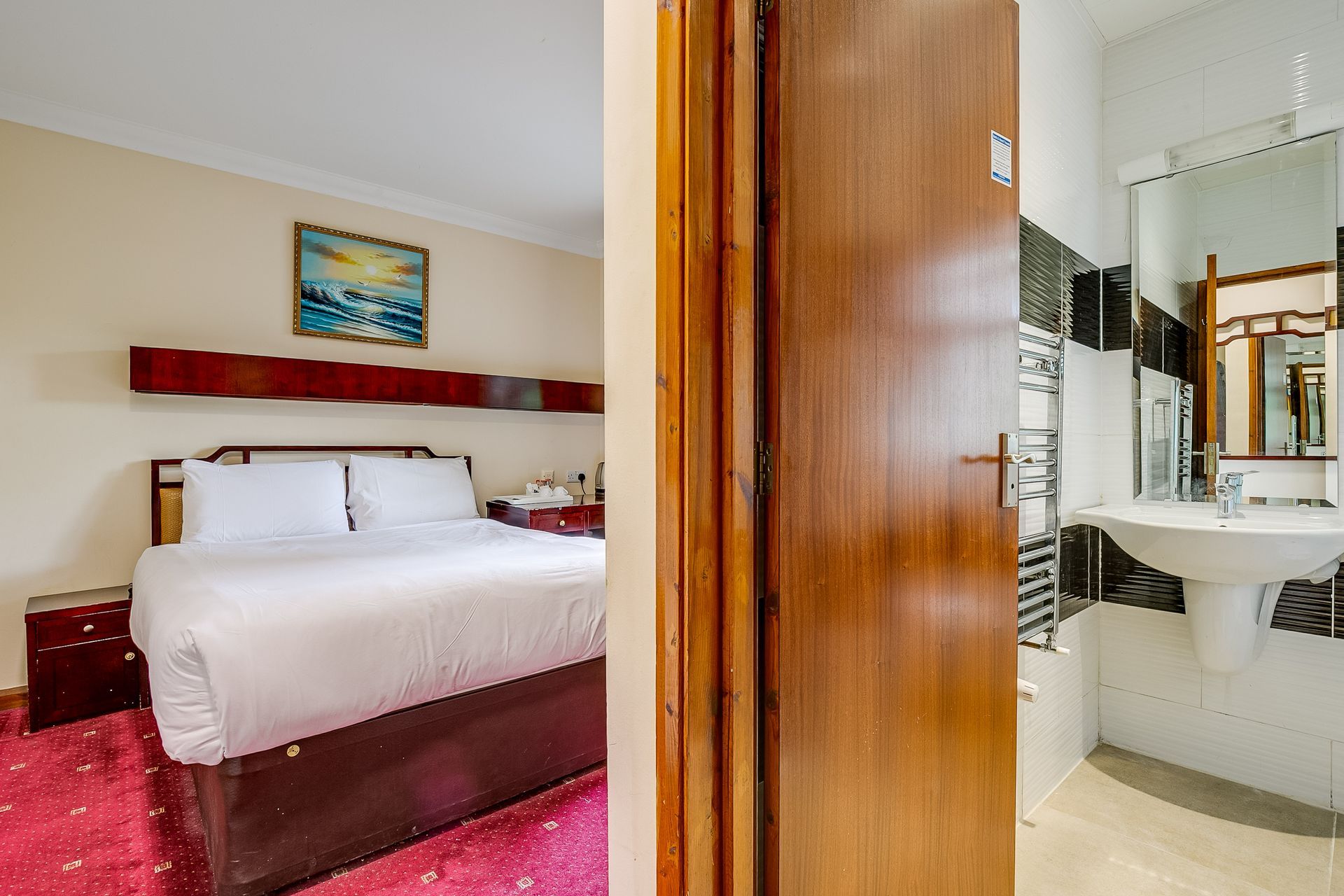 A hotel room with a bed and a bathroom with a sink.
