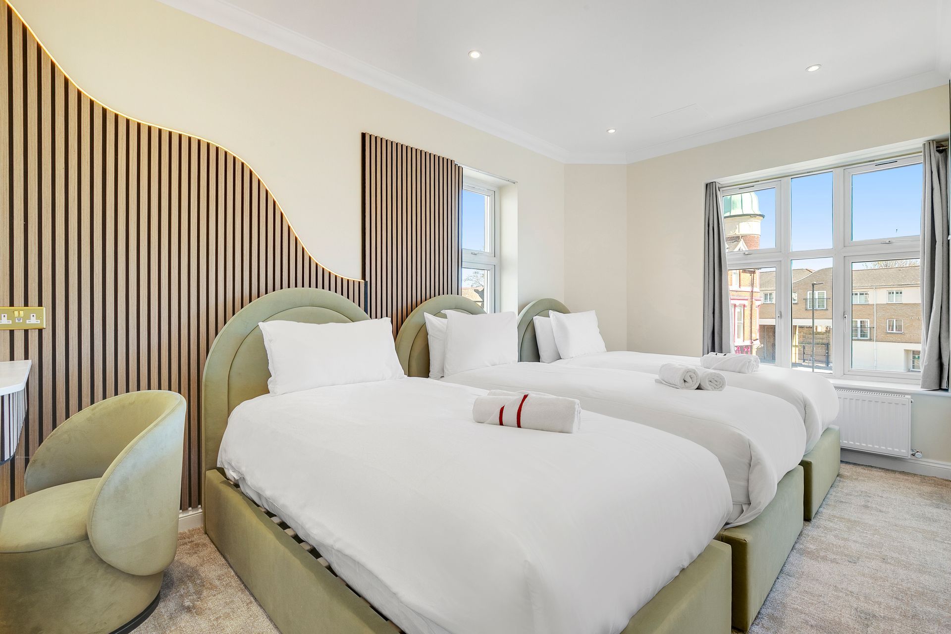 A hotel room with two beds , a chair and a window.