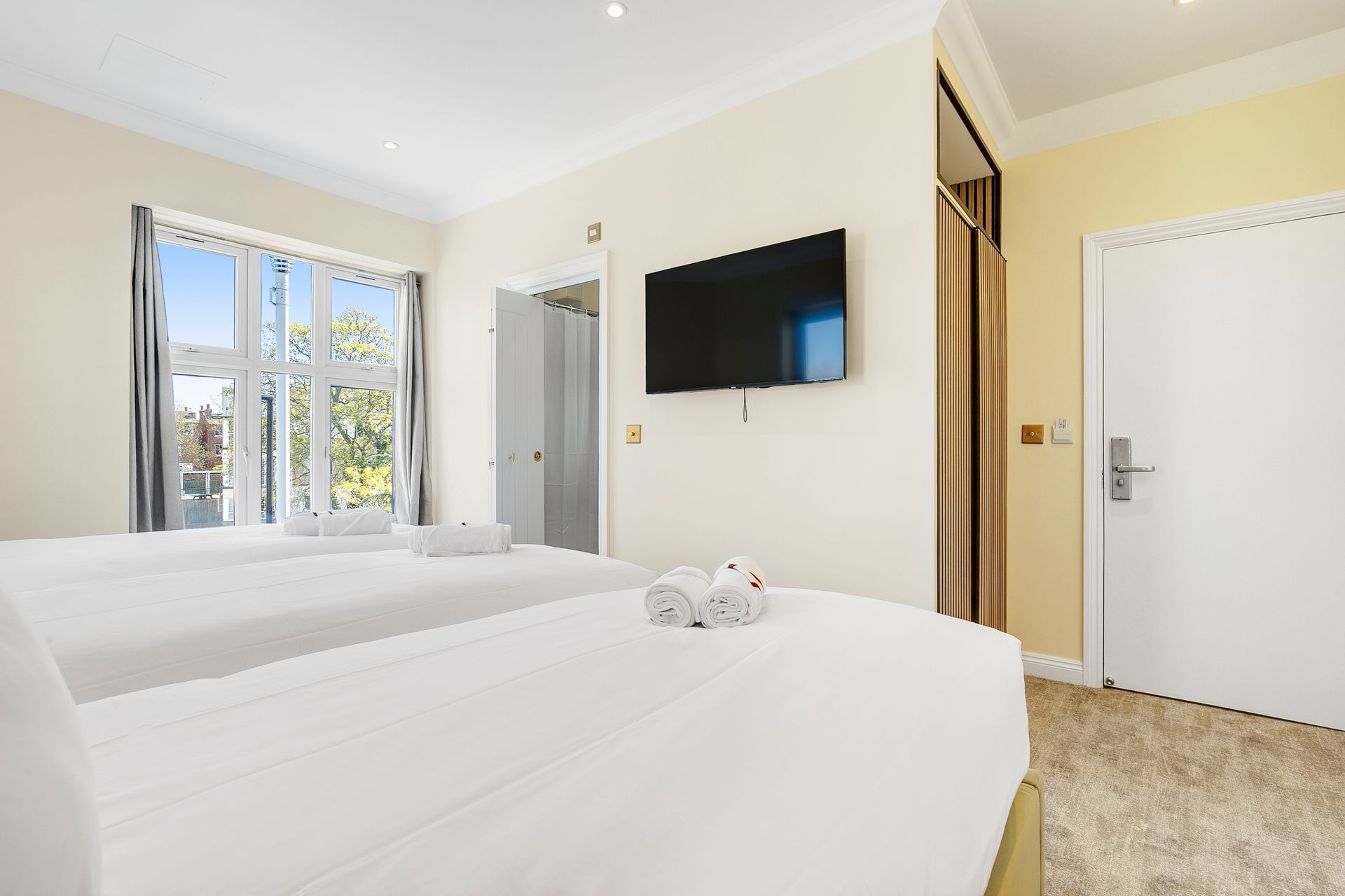 A hotel room with two beds and a flat screen tv on the wall.