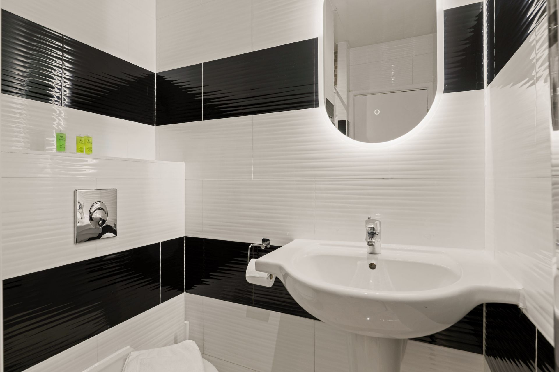 A bathroom with black and white tiles , a sink , toilet and mirror.