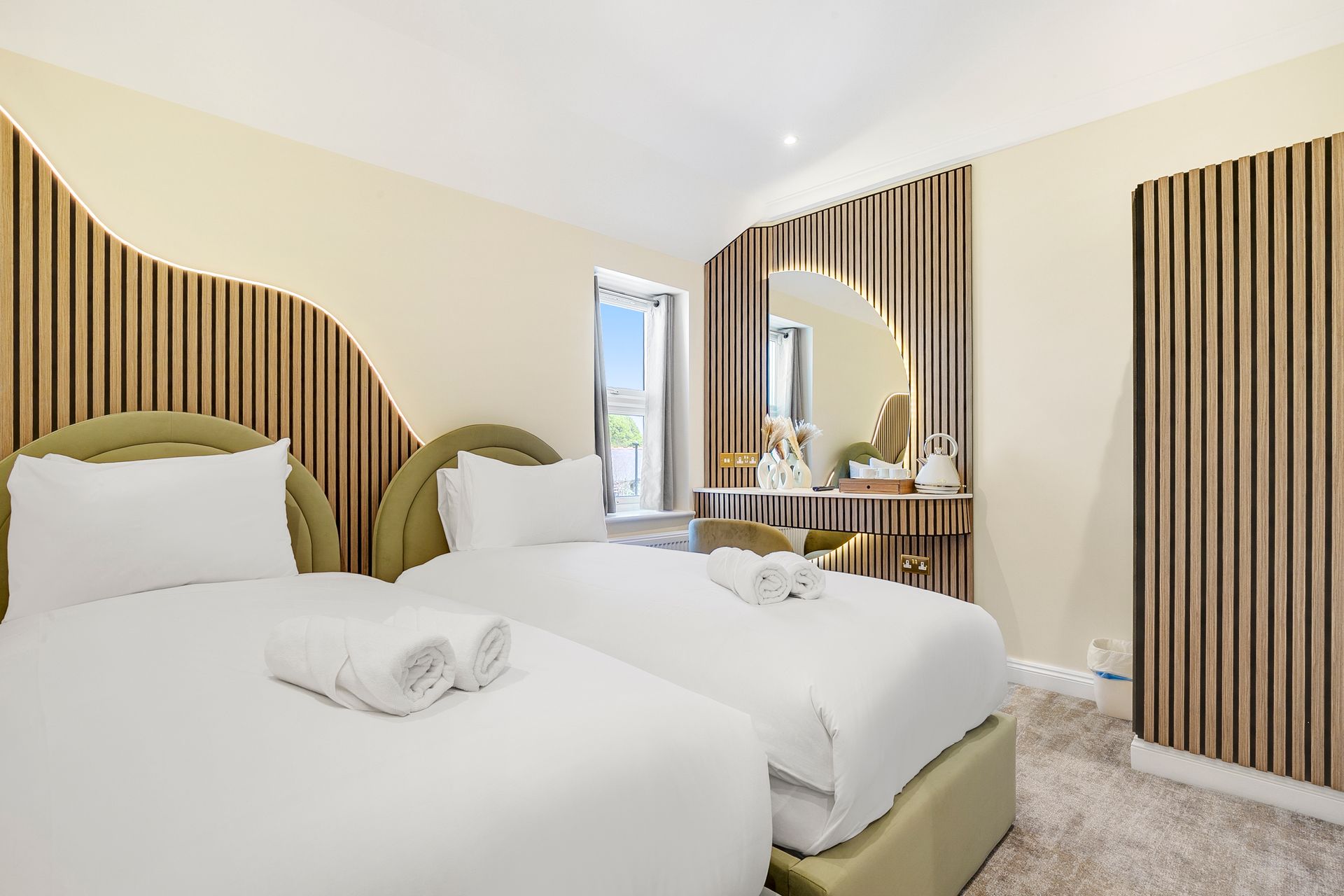 A hotel room with two beds and a mirror.