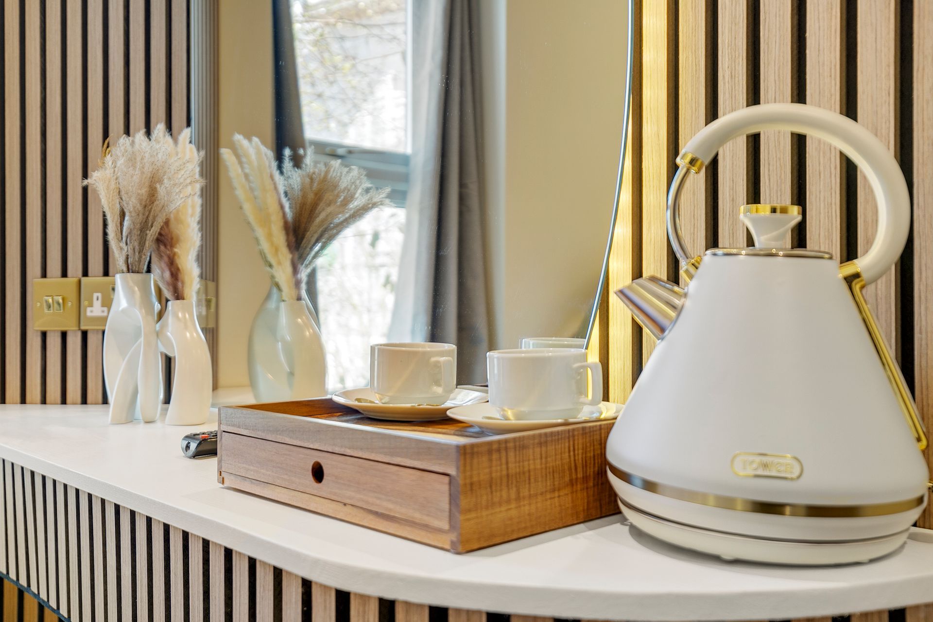 A white kettle is sitting on a counter next to a wooden tray.