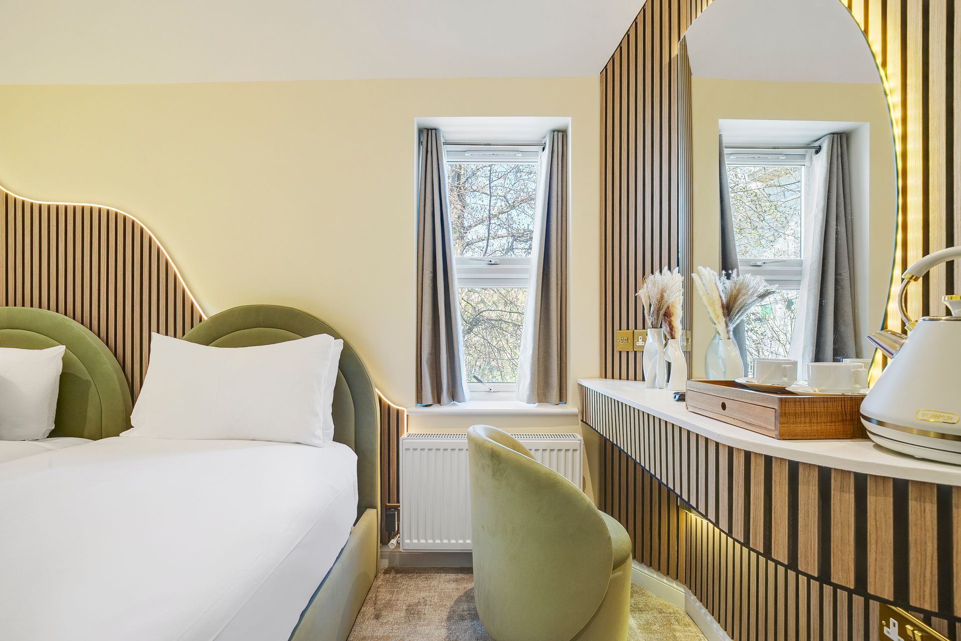 A hotel room with a bed , chair , dresser and mirror.