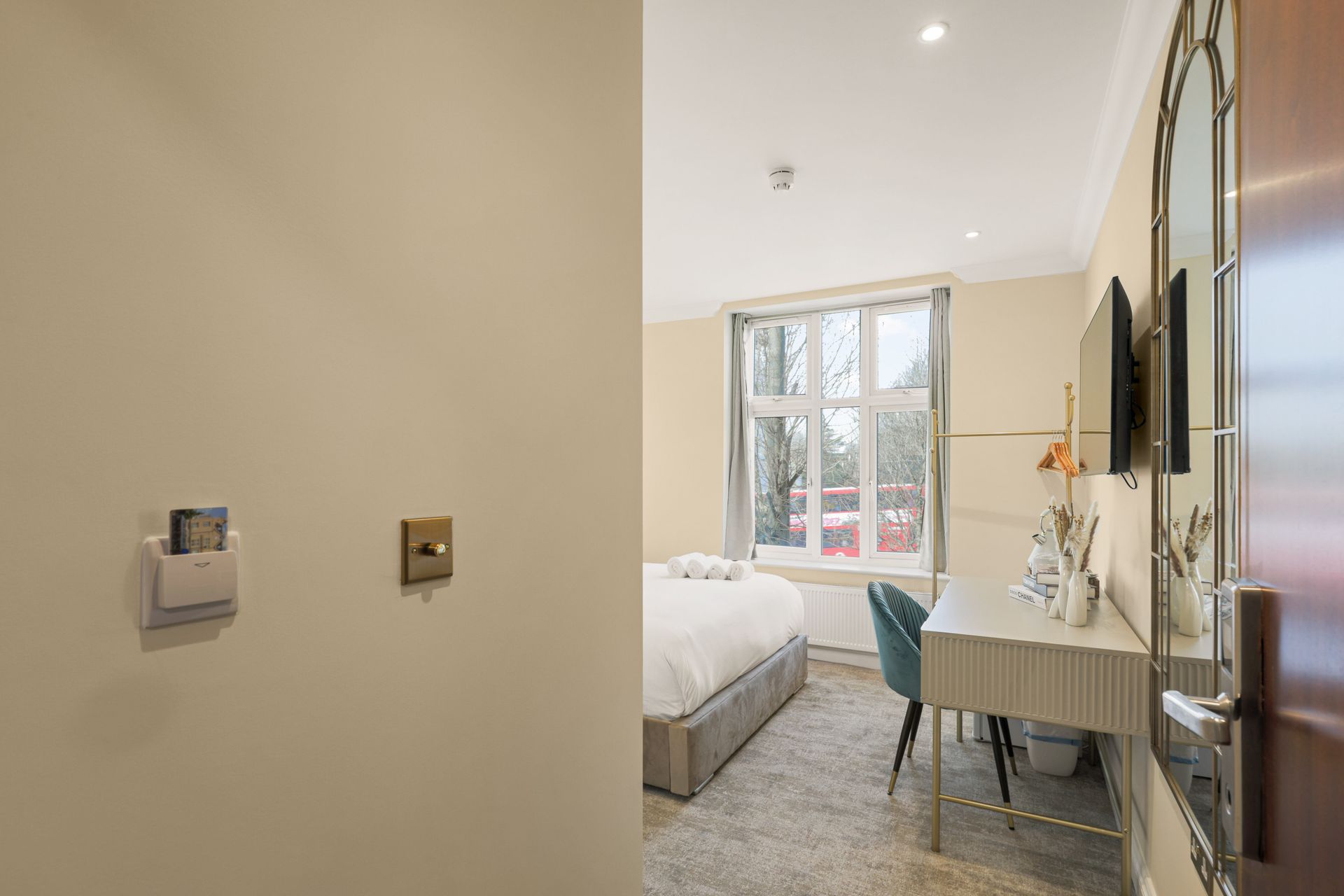 A hotel room with a bed , desk , television and mirror.