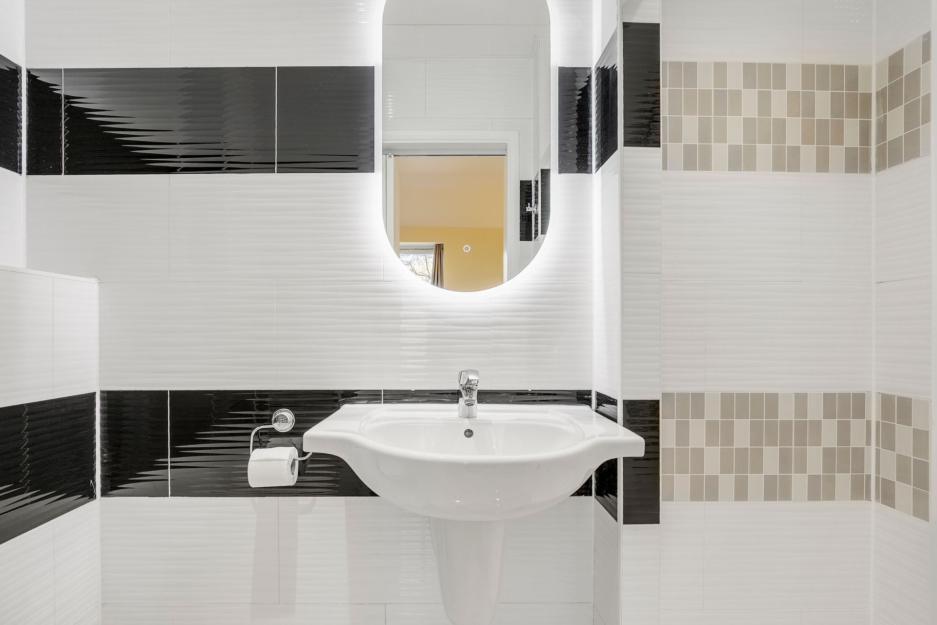A bathroom with a sink , mirror and black and white tiles.