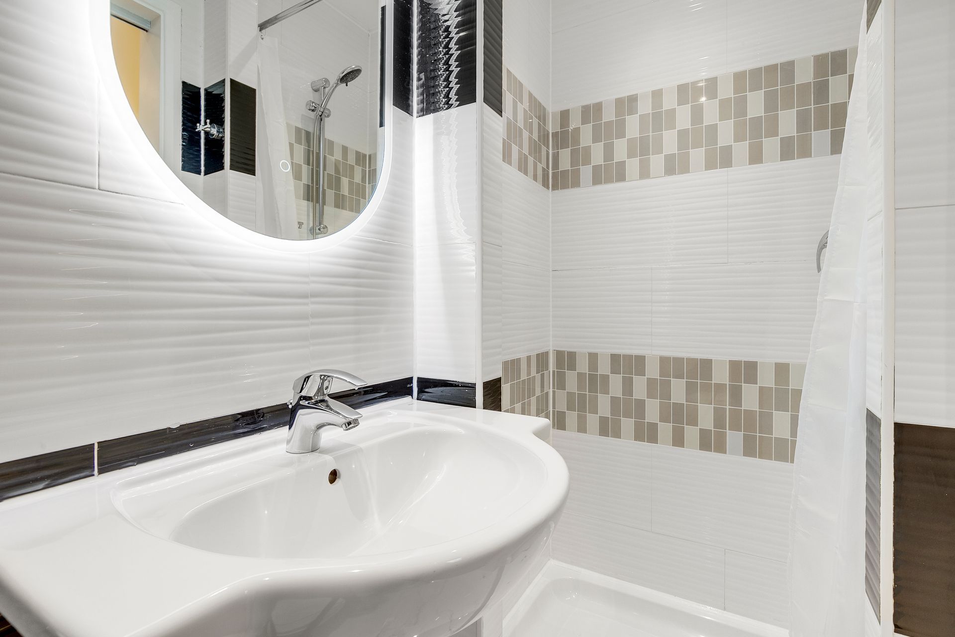 A bathroom with a sink , mirror and shower.