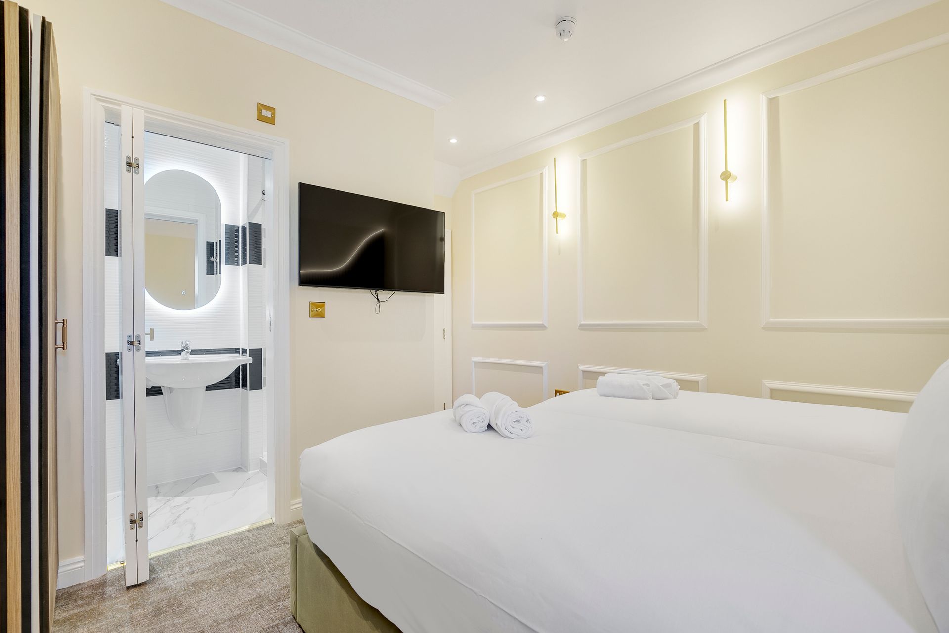 A hotel room with a bed , television , sink and mirror.