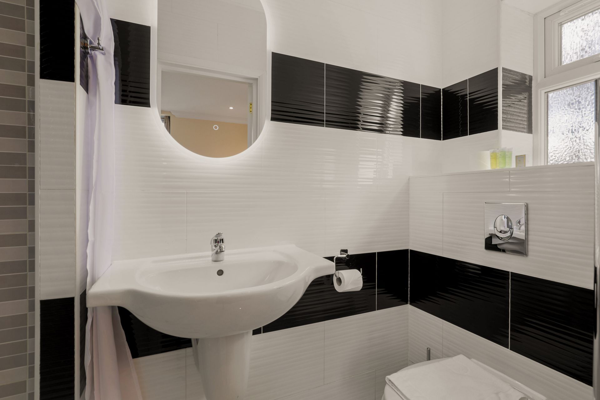 A bathroom with a sink , toilet and mirror.
