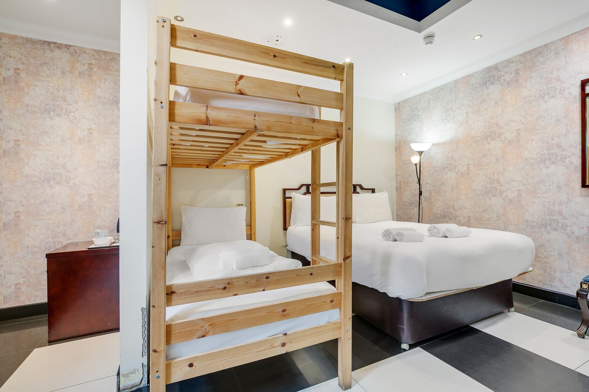 A hotel room with two beds and a bunk bed.